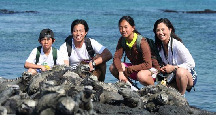 A family posing on rocks by the sea.