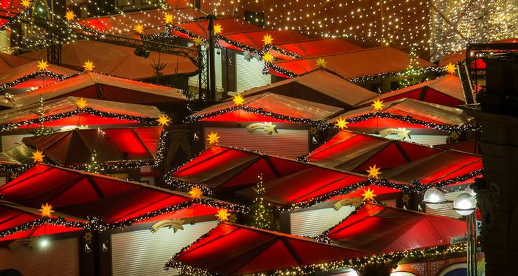 Bunte Reihen festlicher Weihnachtsmarktstände, die nachts mit Lichterketten beleuchtet sind