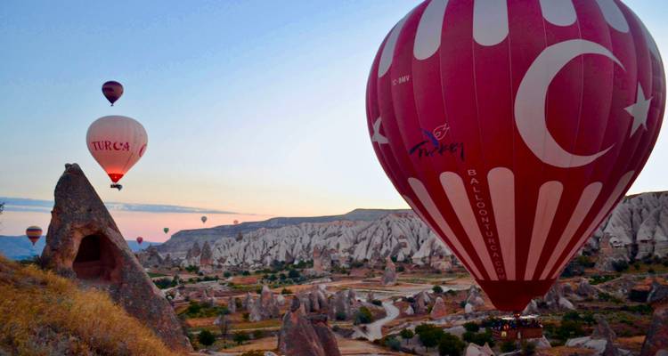 Globos aerostáticos sobre paisaje rocoso al amanecer.