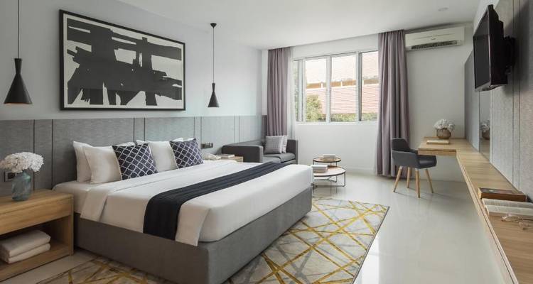 Modern hotel room with a large bed, artwork, and a window letting in natural light.