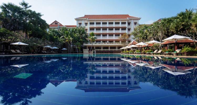 Luxurious hotel with a large outdoor pool and tropical landscaping.