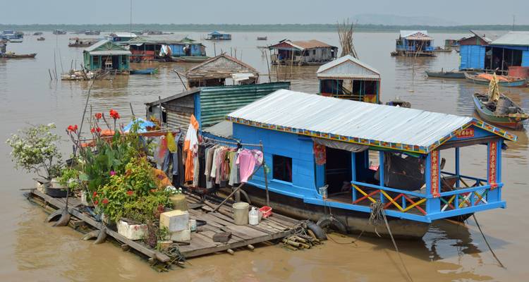 Floating village with colorful houseboats, laundry hanging outside.