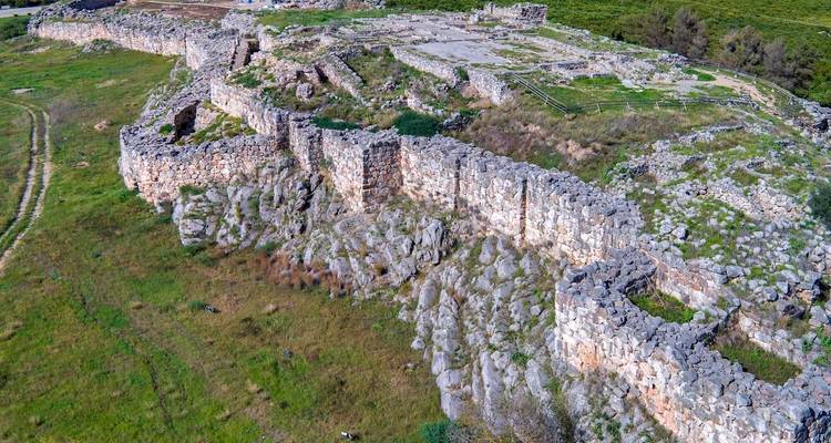 Stone ruins of an ancient city wall on a grassy landscape.