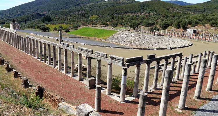 Ruined columns and a theater in an ancient archaeological site.
