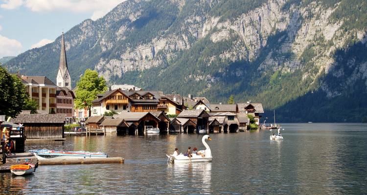 Des personnes sur un lac dans des bateaux avec un charmant village au bord du lac.