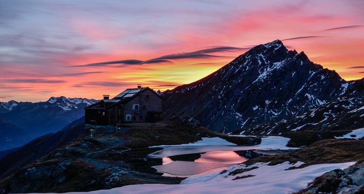 Berghut met adembenemende zonsondergang op de achtergrond.