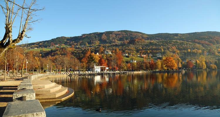 A lake with colorful autumn trees and distant hills.