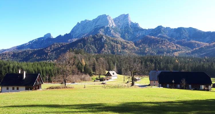 Vue de montagne avec des champs, des maisons et un ciel bleu.