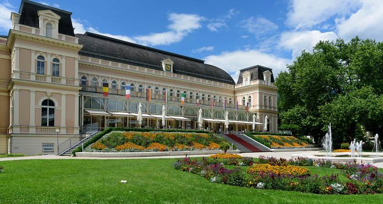 Elegantes Gebäude umgeben von Gärten an einem sonnigen Tag.