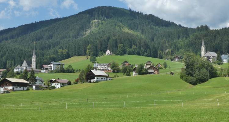 A peaceful hillside town with a church and open green fields.