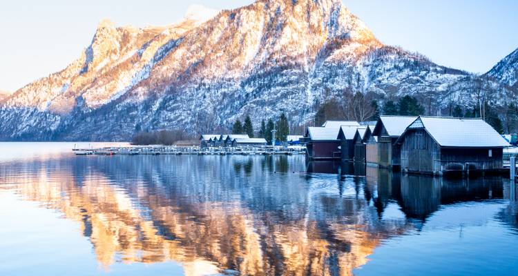Montagnes enneigées et un lac avec les reflets de hangars à bateaux.
