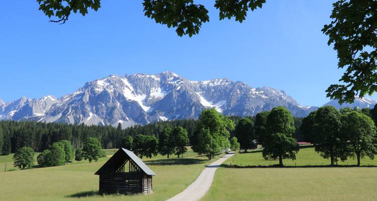 Campagne avec une chaîne de montagnes et une cabane en bois