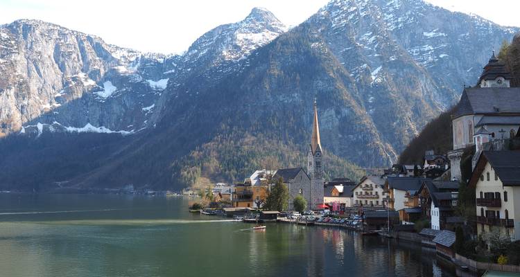 Historic village with a lake and mountains in the distance.