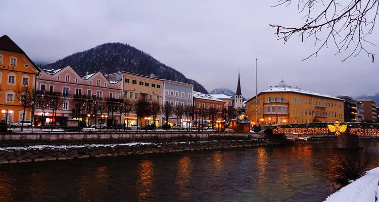 Charming town by a river with snow-capped mountains in the background.