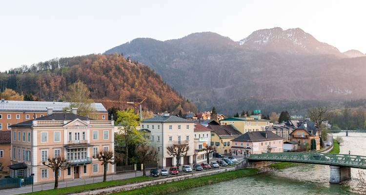 Idyllic town by a river with a bridge, surrounded by hills.