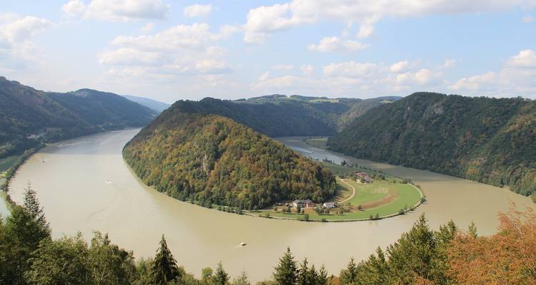 Malerische Aussicht auf einen Fluss, der sich durch ein üppig grünes Tal schlängelt.