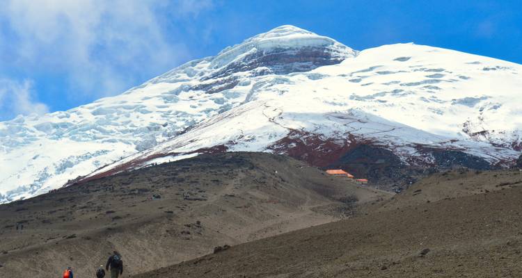 Randonneurs gravissant une montagne volcanique couverte de neige.
