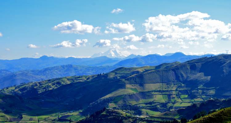 Vue aérienne de montagnes et de vallées sous un ciel parsemé de nuages.