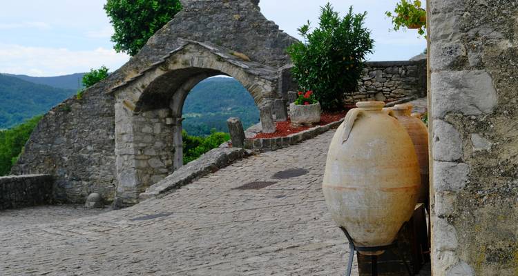 Arche en pierre et pots dans une ville rustique au sommet d'une colline.