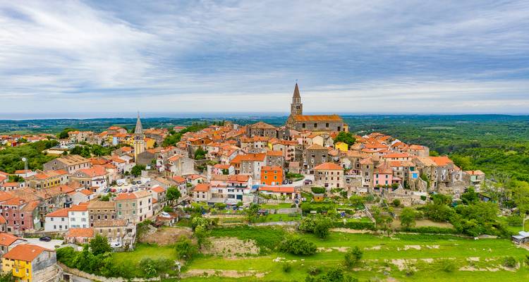 Town with towers on a hill under cloudy sky.
