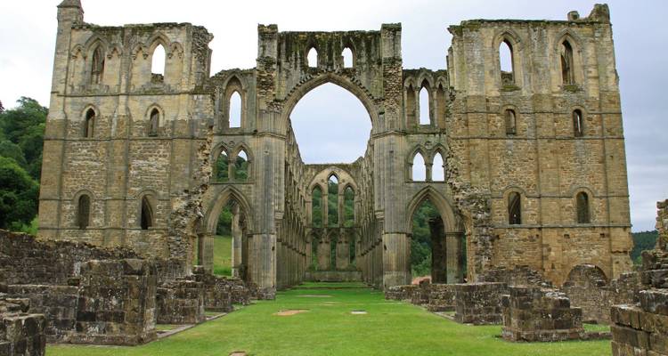 Ruines d'une grande abbaye de pierre avec des arches.
