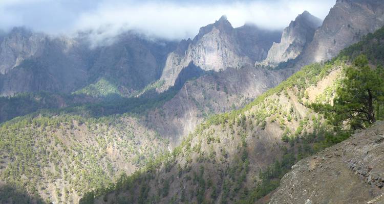 Paysage montagneux dramatique partiellement couvert de nuages.