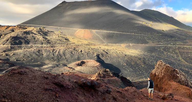 Paysage volcanique avec des collines arides et une personne explorant la zone.