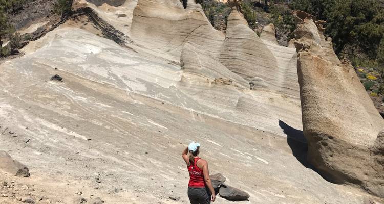 Person observing unique geological formations with pointed peaks made of sedimentary rock.