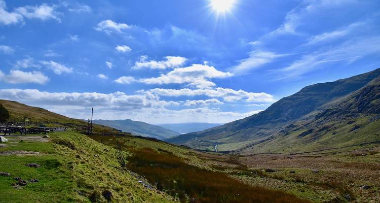 Vue étendue de la vallée et des collines sous un ciel lumineux.