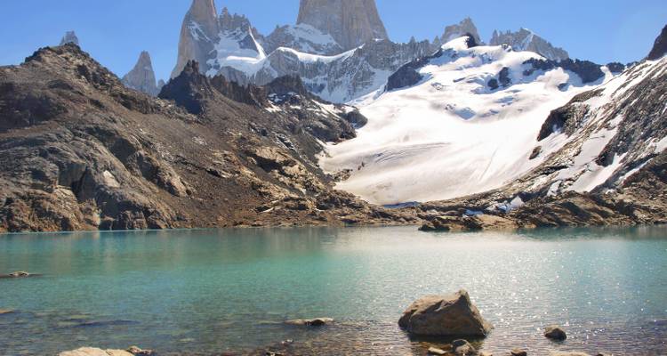 Mountain range with snowy peaks and a turquoise lake in the foreground.