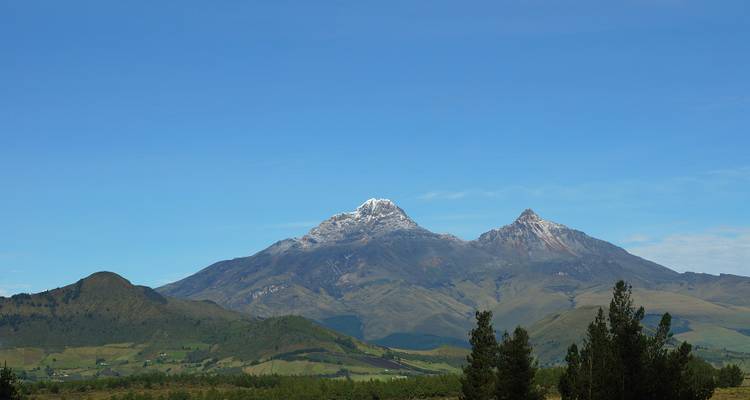 Tall mountain peaks with snow caps surrounded by green and rocky landscape.
