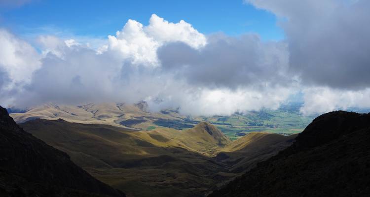 Dramatic valley landscape with sunlight breaking through clouds onto hills.