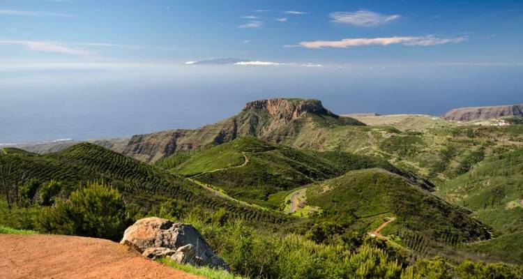 Sentier de randonnée à travers un paysage vallonné verdoyant.