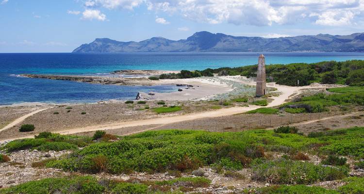 Littoral avec un décor de montagnes et une tour solitaire.