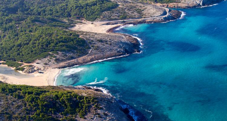 Vue aérienne d'une plage aux eaux turquoise et à l'environnement luxuriant.
