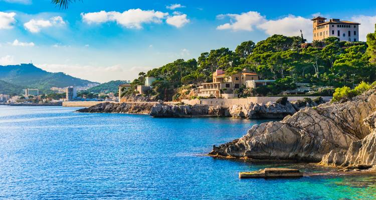 Paysage côtier avec maisons de luxe sur des falaises rocheuses au bord de la mer.
