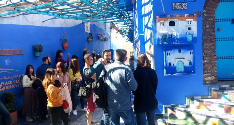 Touristen erkunden lebendige blaue Straßen mit Kunstwerken.