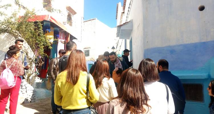 Menschenmenge in einer bunten Gasse, wahrscheinlich eine Reisegruppe, die einem Führer zuhört.