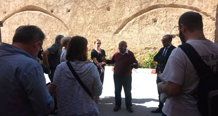 Reisegruppe, die einem Führer in historischer Umgebung zuhört.