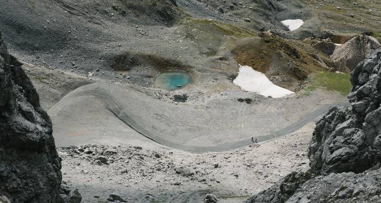 Hochgelegene Felsenlandschaft mit einem kleinen türkisfarbenen Teich.