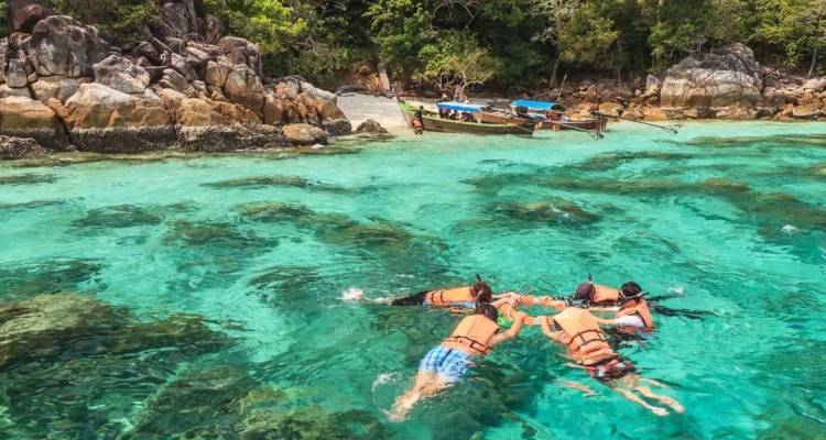 Snorkelers drijvend boven kristalhelder turquoise water bij een rotsachtig Thais eiland