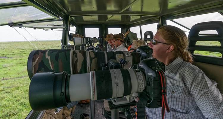 Groep fotografen met camera's in een safarivoertuig.