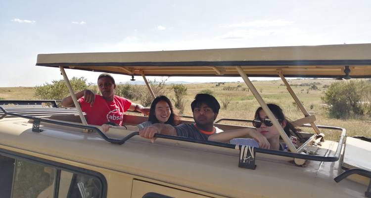 Toeristen in een safarivoertuig in een open veld.