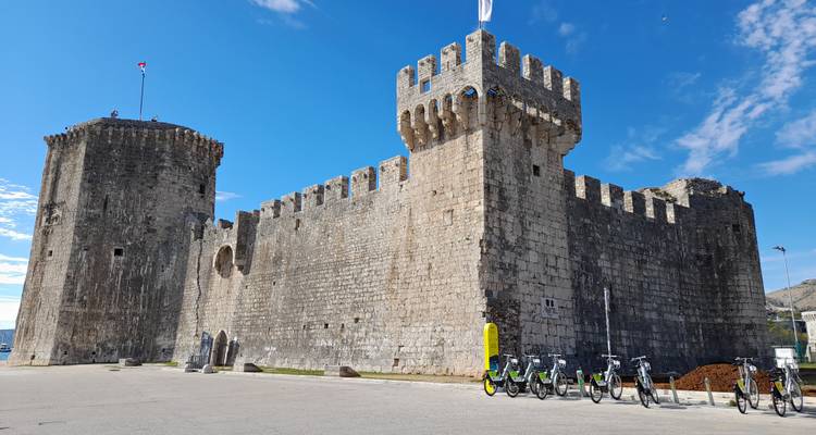 Stenen Kamerlengo Fort met huurfietsen geparkeerd buiten onder een levendige blauwe lucht