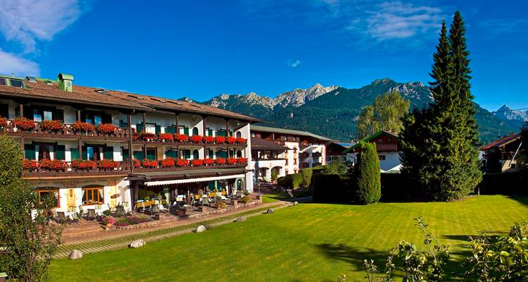 Hôtel alpin avec des fleurs colorées et un décor de montagnes en arrière-plan.