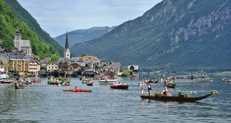 Des bateaux sur un lac avec un village pittoresque et des montagnes.
