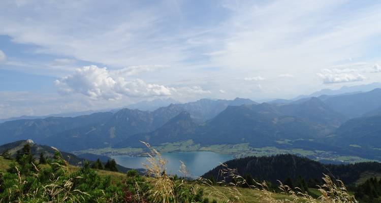 Een uitzicht over een vallei en meer met bergen op de achtergrond.