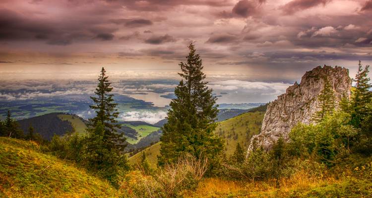 A mountain view with dramatic skies and a distant lake.