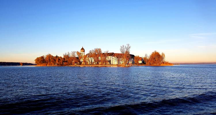 An island in a large lake with a historic building at sunset.
