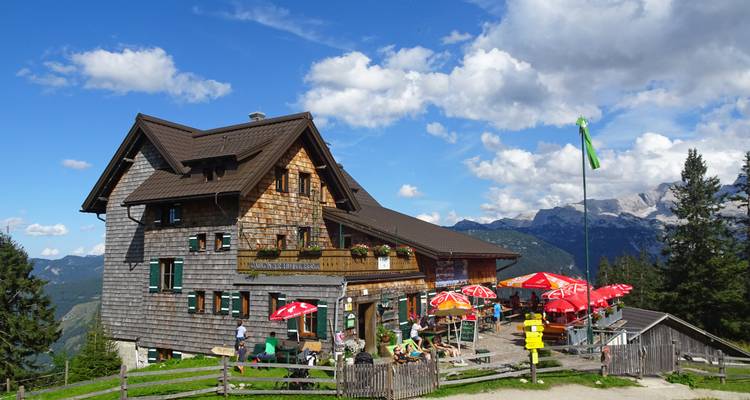 Berghut met buitenterras en parasols.